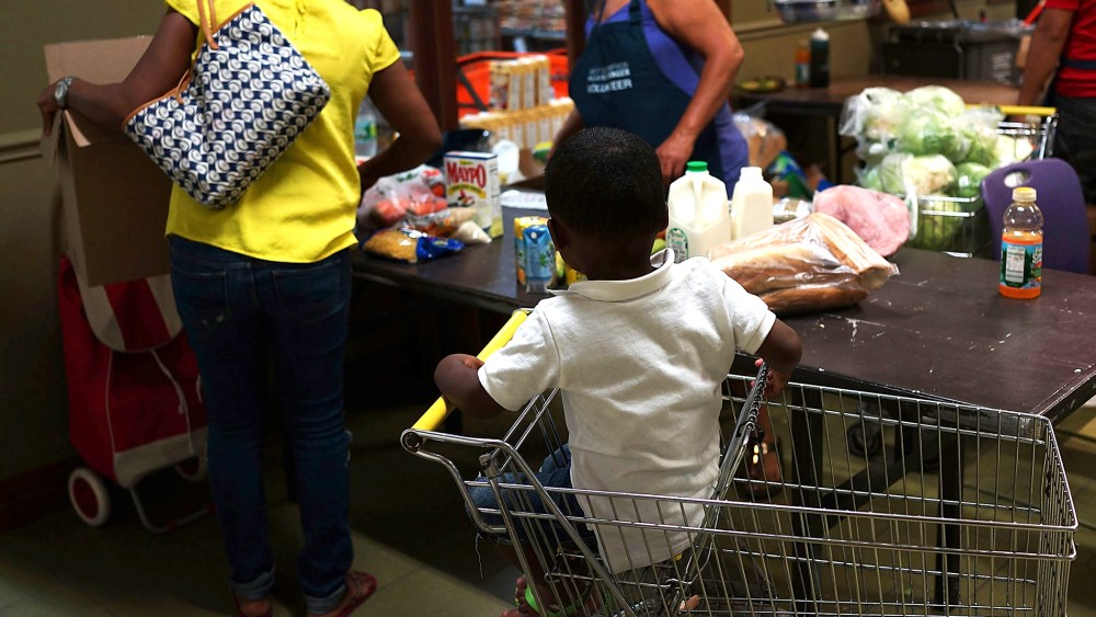 A child watches as his mother at the West Side Campaign Against Hunger food pantry as she shops for food on July 24, 2013 in New York, N.Y.