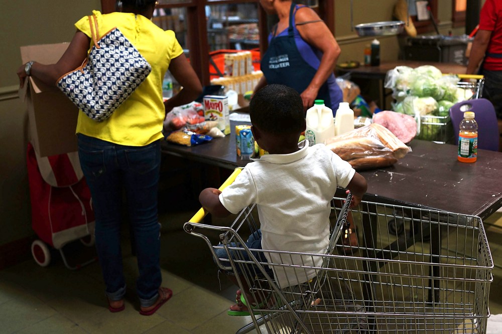 A child watches as his mother at the West Side Campaign Against Hunger food pantry as she shops for food on July 24, 2013 in New York, N.Y.