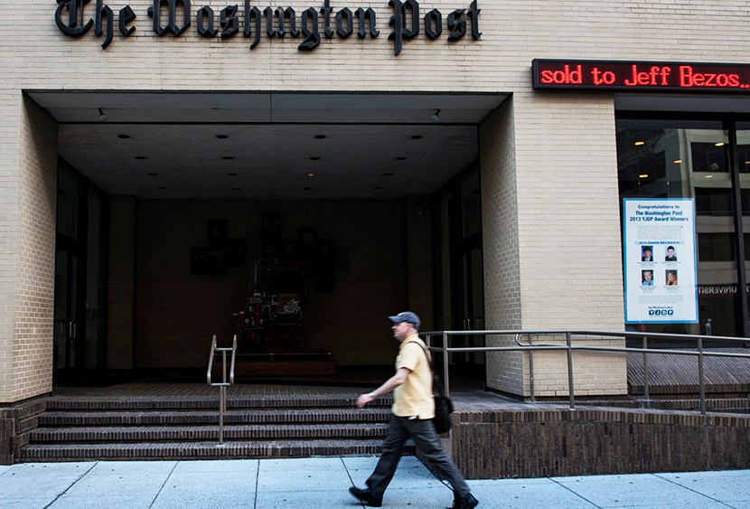 A man walks past The Washington Post building on August 5, 2013 in Washington, DC, after it was announced that Amazon.com founder and CEO Jeff Bezos had agreed to purchase the Post for USD 250 million. (Photo by Brendan Smialowski/AFP/Getty)