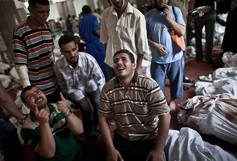 Egyptians mourn at a mosque in Cairo where lines of bodies wrapped in shrouds are laid out on August 15, 2013, following a crackdown on the protest camps of supporters of ousted Islamist president Mohamed Morsi the previous day. (Photo by Mahmoud...