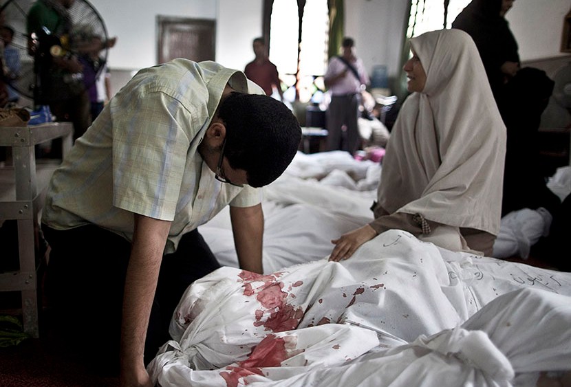 Egyptians mourn over a body wrapped in shrouds at a mosque in Cairo on August 15, 2013, following a crackdown on the protest camps of supporters of ousted Islamist president Mohamed Morsi the previous day.  (Photo by Mahmoud Khaled/AFP/Getty Images)