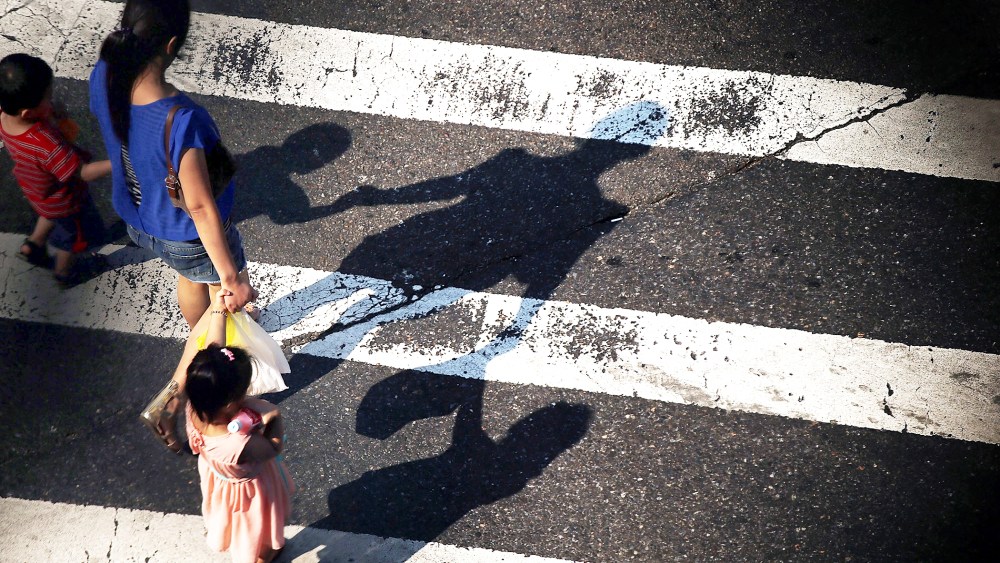 A woman crosses a street with children as seen from the Manhattan Bridge in New York City, on Aug. 21, 2013.