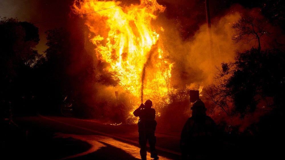 A firefighter sprays water as a wildfire races along Lytle Creek Road near Keenbrook, Calif., Aug. 17, 2016. (Photo by Noah Berger/AP)