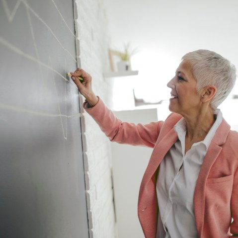 Businesswoman Drawing Chart On Blackboard In Her Office.
