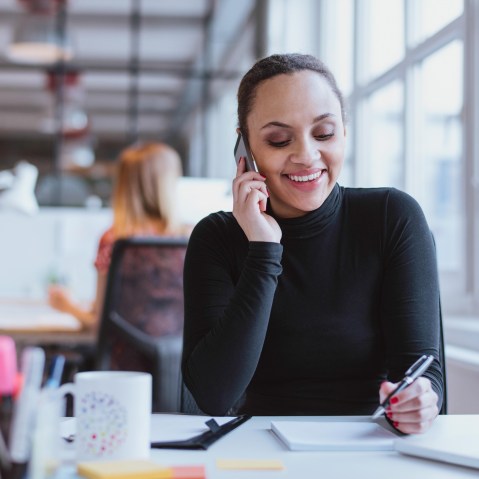 Image: A woman speaks on the phone in an office.