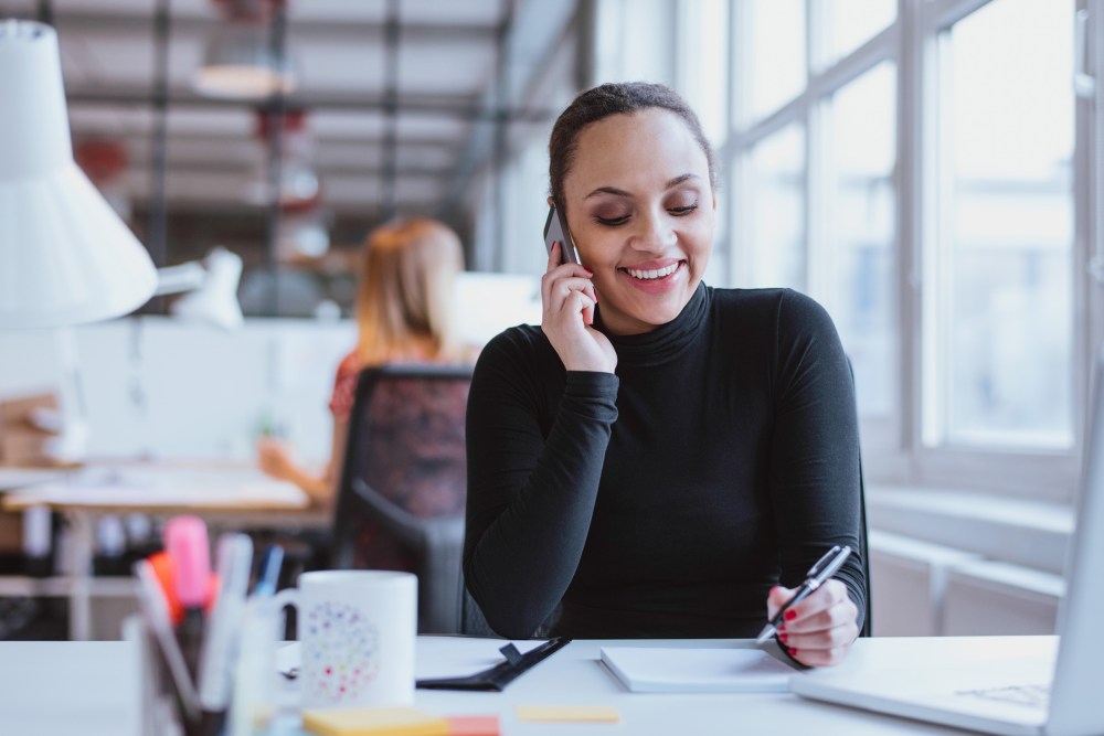 Image: A woman speaks on the phone in an office.