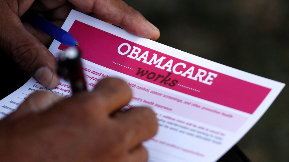 Image: A man fills out an information card during an Affordable Care Act outreach event