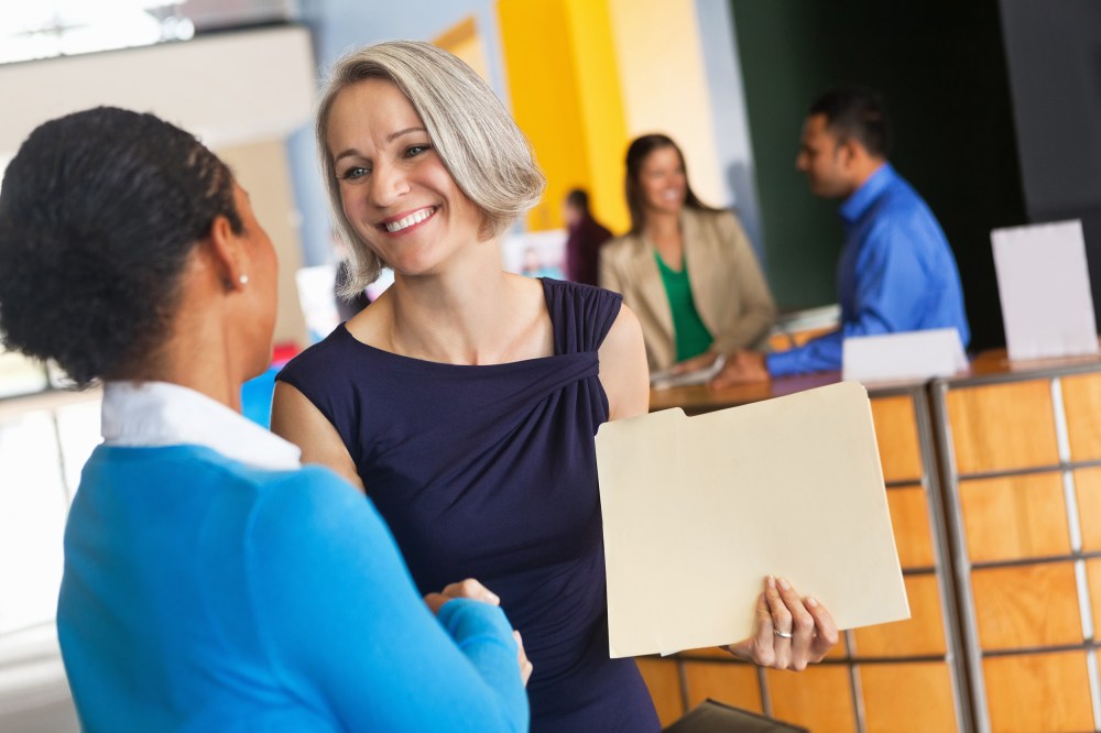 Image: Mature businesswoman shaking hands with prospective employee at job fair