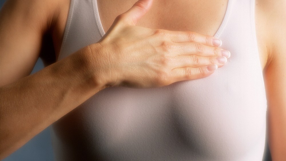 Woman examining breast, mid-section, close-up