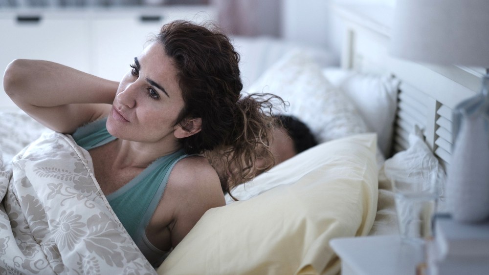 Image: Woman rubbing her neck in bed