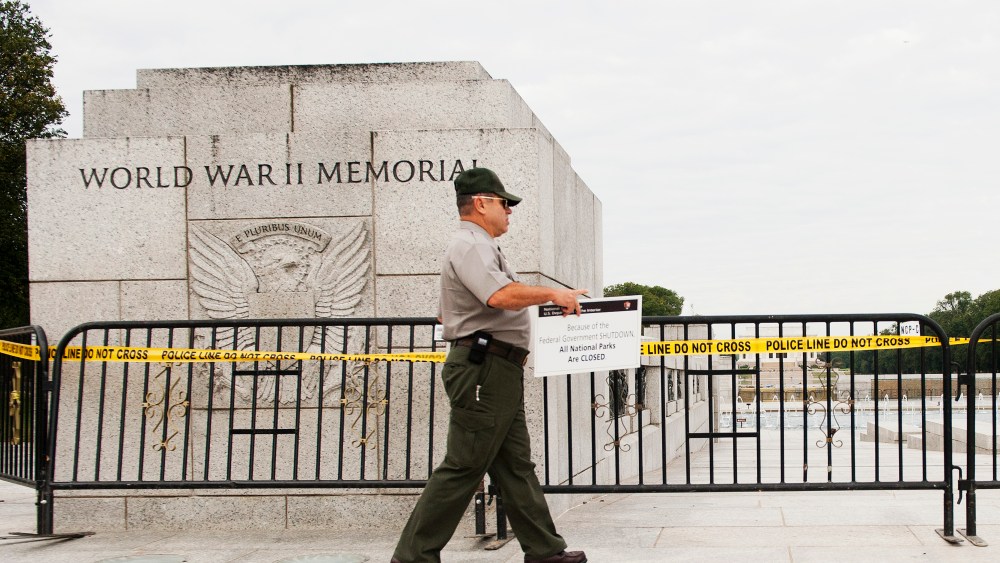 US Park Ranger Richard Trott places a closed sign on a barricade in front of the World War II Memorial monument in Washington, DC, October 1, 2013.