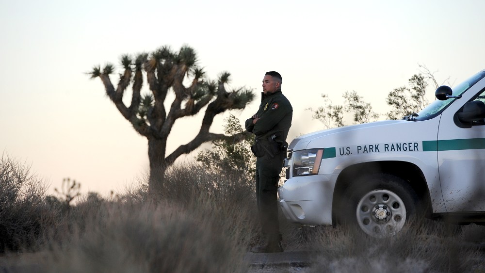 Park Ranger Dylan Moe stands guard as the sun sets at the entrance to Joshua Tree National Park