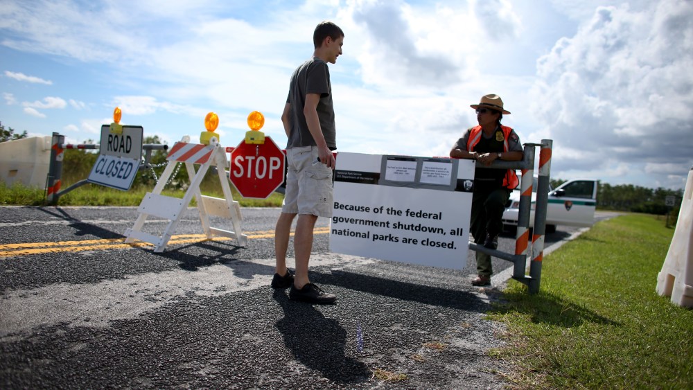 Mirta Maltes a U.S. Park Ranger law enforcement officer speaks with Christoph Zuercher, a tourist from Switzerland, at a road closed sign leading to the Everglades National Park after he discovered the park was closed on October 7, 2013 in Miami, Florida.