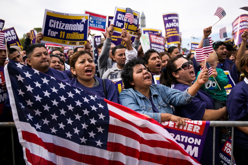 Lorena Ramirez, of Arlington, Virginia, holds up an American flag as she cheers with her friend Lilia Beiec during a rally in support of immigration reform, in Washington, on October 8, 2013 in Washington, DC.