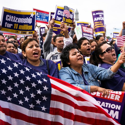 (L to R) Lorena Ramirez, of Arlington, Virginia, holds up an American flag as she cheers with her friend Lilia Beiec during a rally in support of immigration reform on October 8, 2013 in Washington, D.C. (Photo by Drew Angerer/Getty)