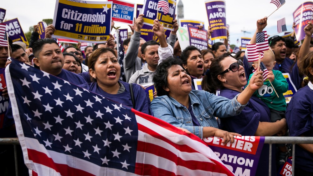 Lorena Ramirez, of Arlington, Va., holds up an American flag as she cheers with her friend Lilia Beiec during a rally in support of immigration reform on Oct. 8, 2013 in Washington, DC. (Drew Angerer/Getty)