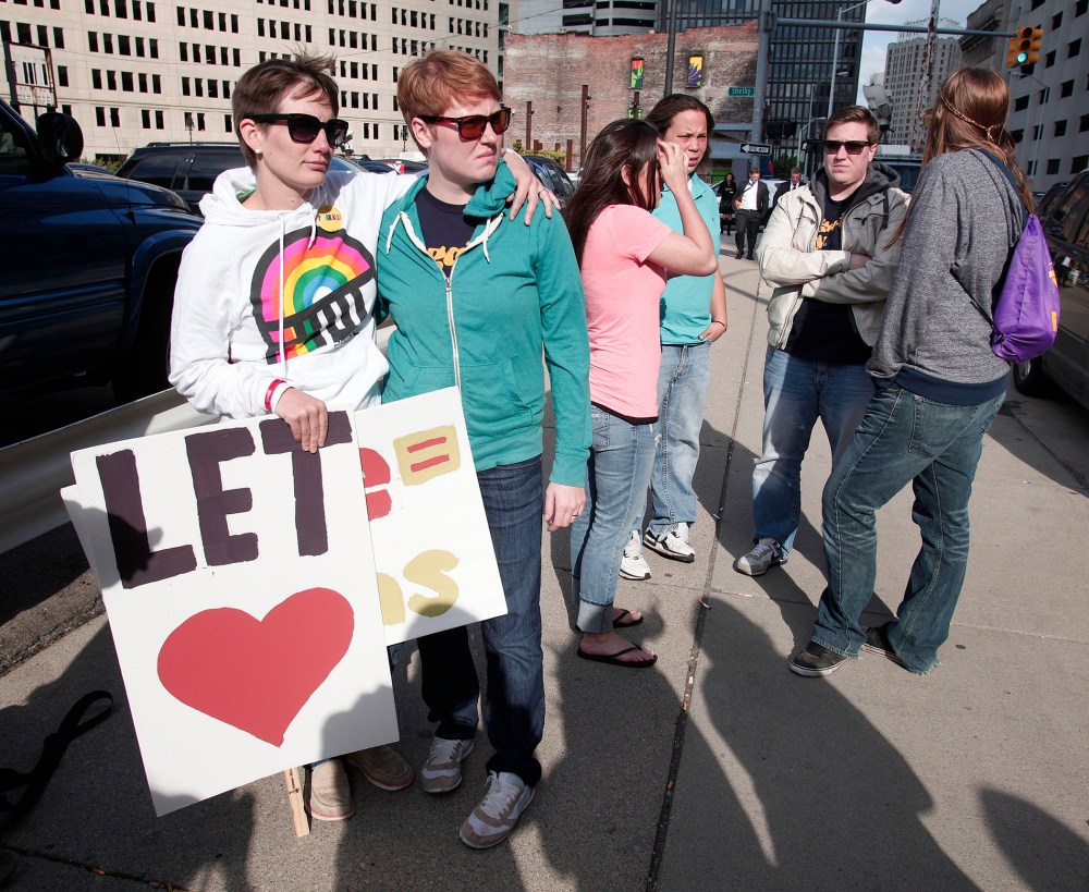 Two women who are married to each other react to the news that a case that could possibly have overturned Michigan's ban on same-sex marriages will go to trial instead of an immediate ruling, at the U.S. Courthouse October 16, 2013 in Detroit, Michigan.