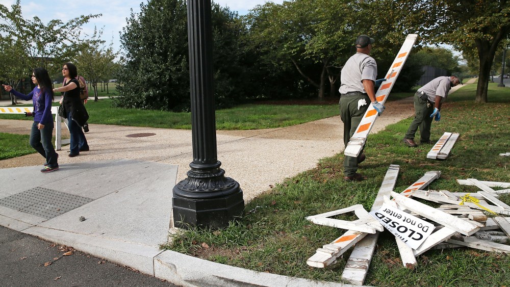 Tourists walk past as U.S. Park Service workers remove barricades on October 17, 2013 in Washington, DC.