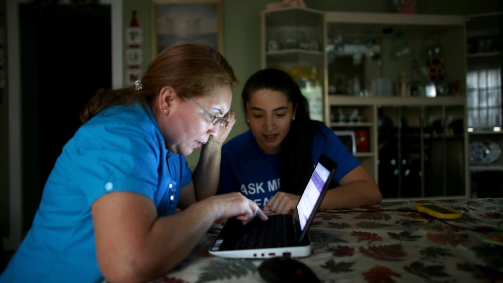 Janelle Arevalo (R), an insurance agent with Sunshine Life and Health Advisors, makes a house call to sign up Sandra Berrios for an insurance plan under the Affordable Care Act on Nov. 14, 2013 in Miami, Fla.
