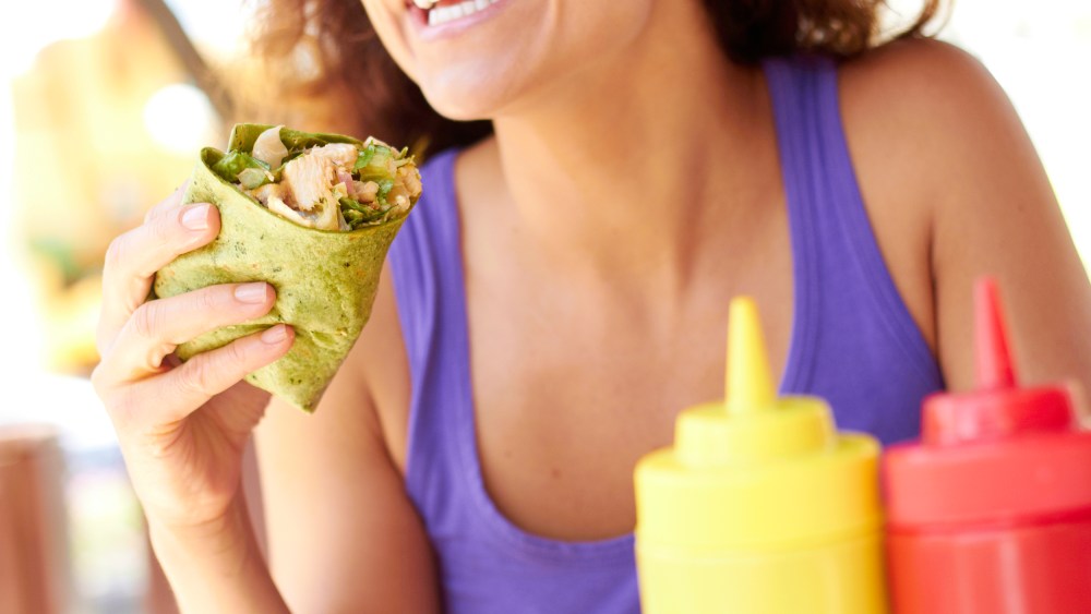 Image: Woman Holding Chicken Wrap in a green spinach tortilla