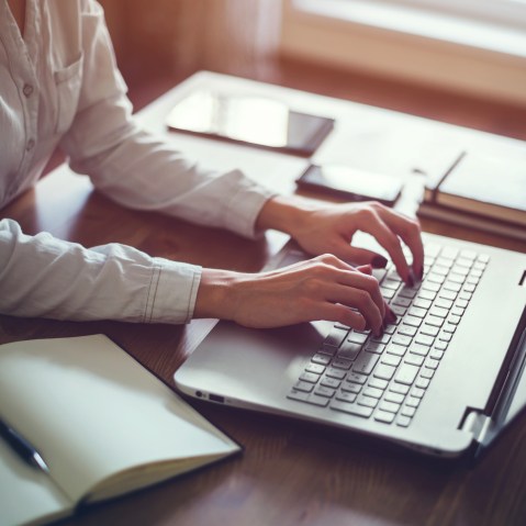Image: Woman working in home office hand on keyboard close up