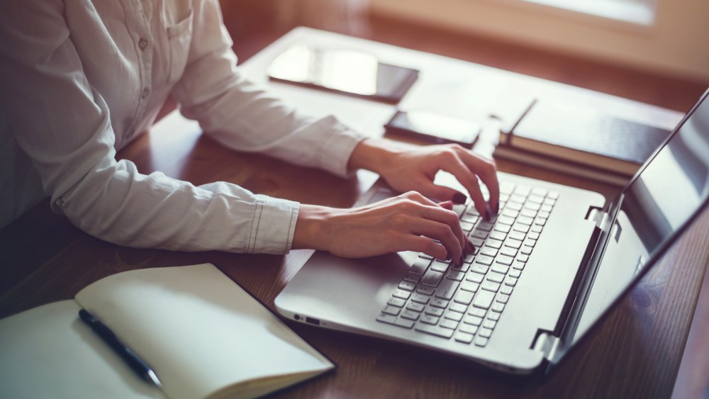 Image: Woman working in home office hand on keyboard close up