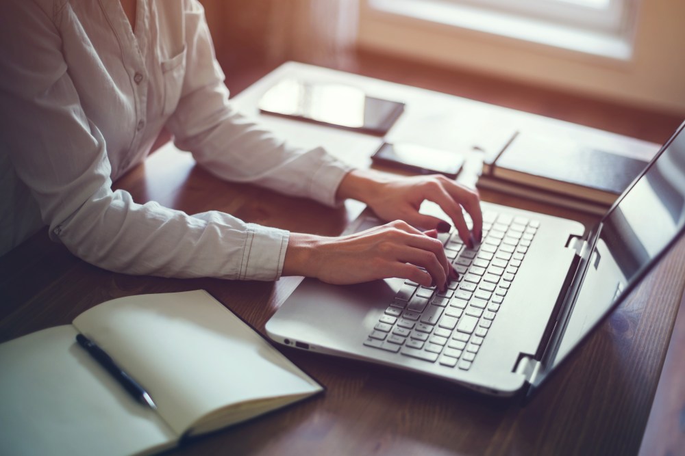 Image: Woman working in home office hand on keyboard close up