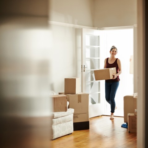 Image: Woman carrying boxes into her new home.