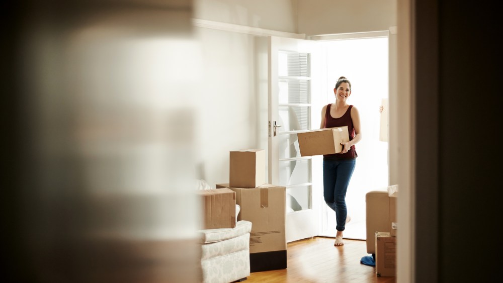 Image: Woman carrying boxes into her new home.