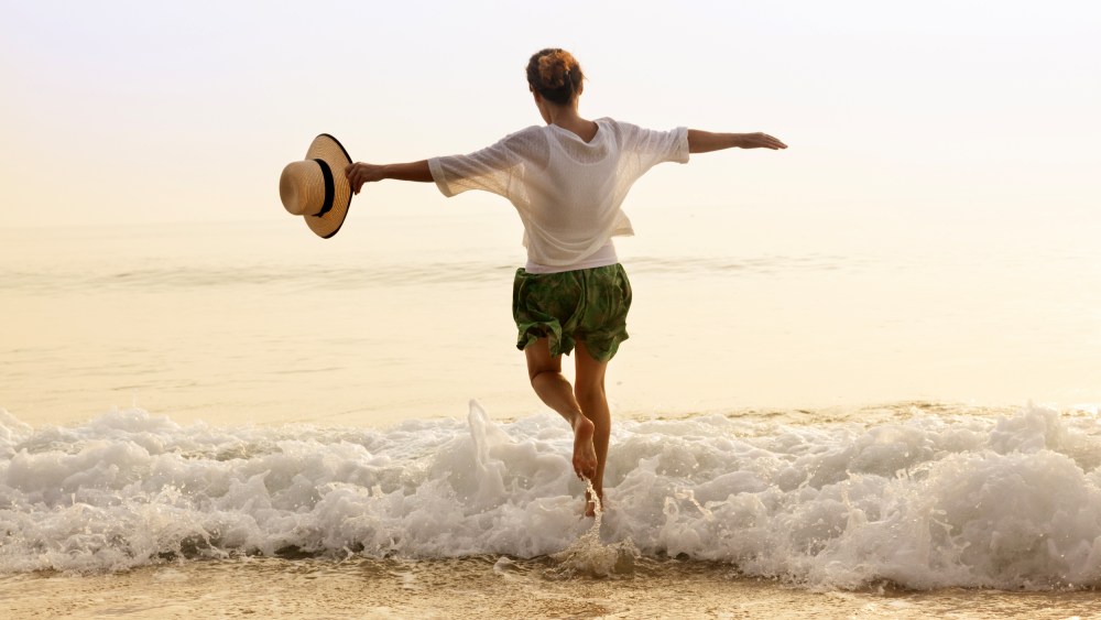 Happy woman with straw hut on beach