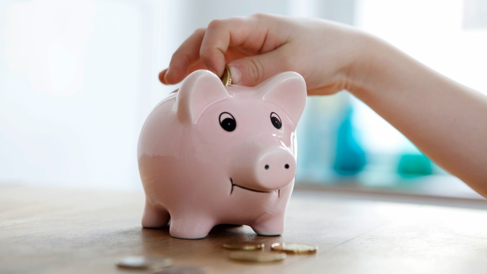 Image: Little boy putting coin into piggy bank, close-up
