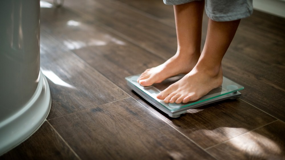 Image: Boy checking his weight on weight scale