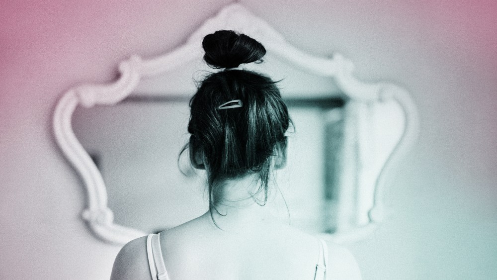 Young woman looking in the mirror