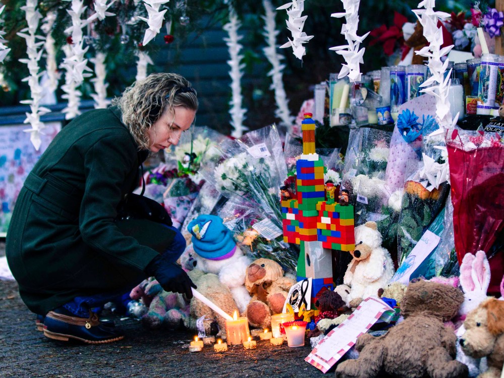 A woman lights candles while visiting a memorial to the victims of the recent shooting in Sandy Hook Village in Newtown, Connecticut December 17, 2012. The small Connecticut town shattered by an act President Barack Obama called "unconscionable evil,"...
