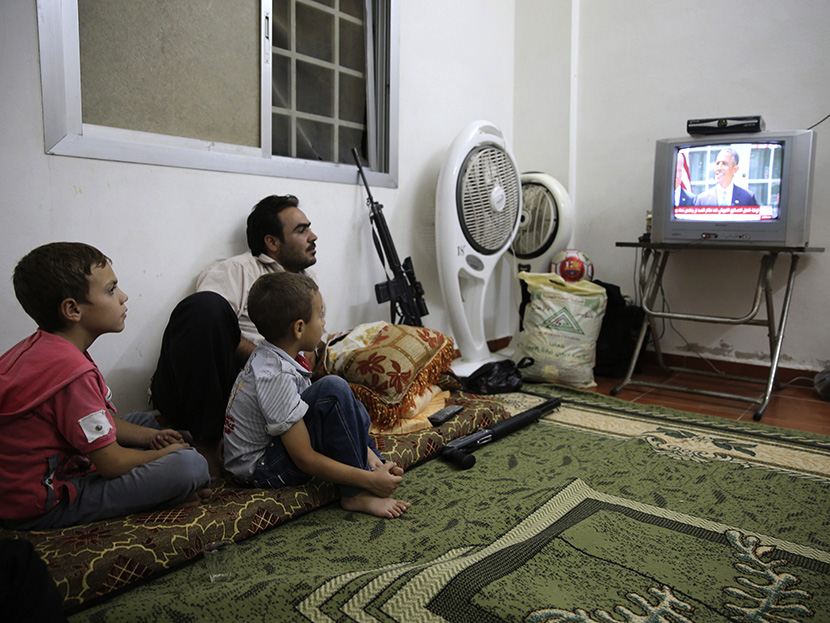 Image: A Free Syrian Army fighter watches U.S. President Barack Obama's speech with his family in Damascus