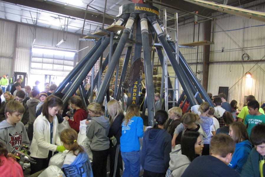 Students from Discovery Middle School in Fargo, N.D., help tie and stack sandbags around a 