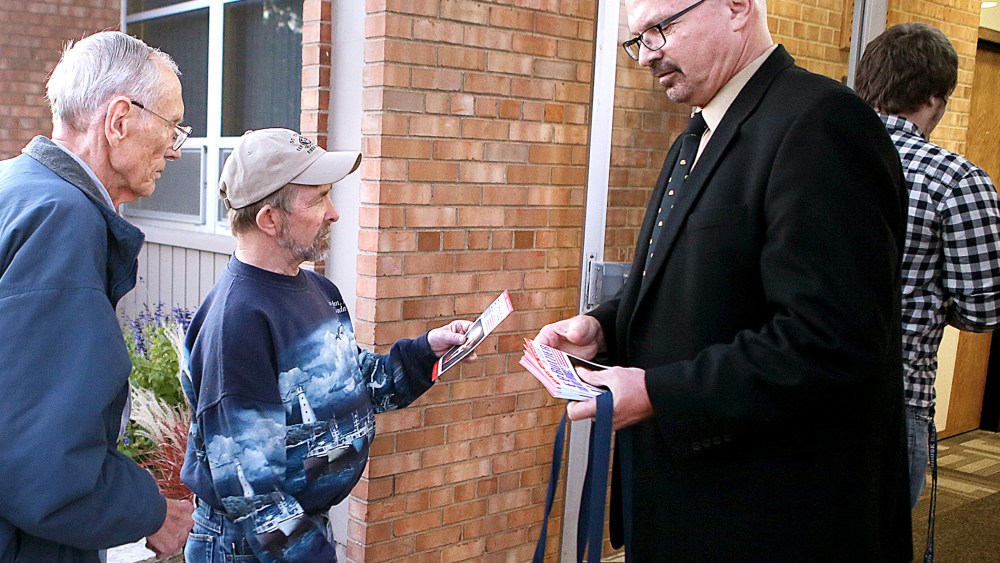U.S. Senate candidate Dr. Doug Butzier, of Dubuque, right, hands out his campaign information in Davenport, Iowa on Oct. 11, 2014.