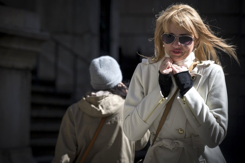 People walk through the wind and cold on Wall Street in New York's financial district on March 19, 2015.