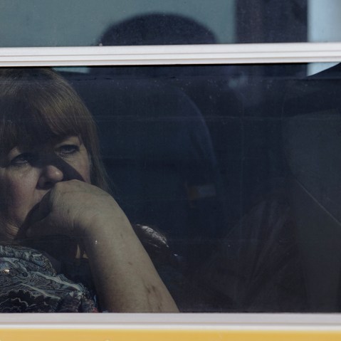 A woman gazes outward as she and others are put onto school buses as they evacuate the site of a shooting with reports of up to 14 people dead at Inland Regional Center. (Photo by Ed Crisostomo/The Orange County Register/ZUMA)