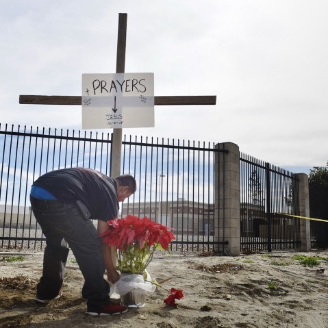 Manny Guzman places flowers near a cross he put up off Waterman Ave near the site of Wednesday's mass shooting in San Bernardino, Calif., Dec. 3, 2015. (Photo by Stuart Palley/ZUMA)