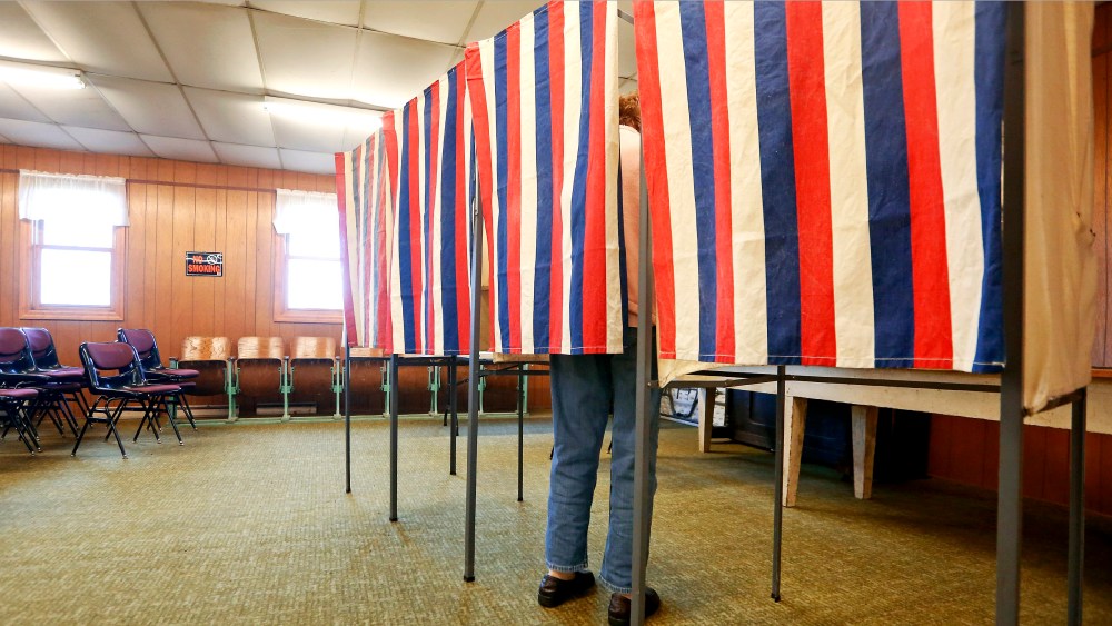 A voter casts a ballot behind a curtain at Smelser Town Hall, Nov. 8, 2016, in Georgetown, Wis. (Photo by Nicki Kohl/Telegraph Herald/AP)
