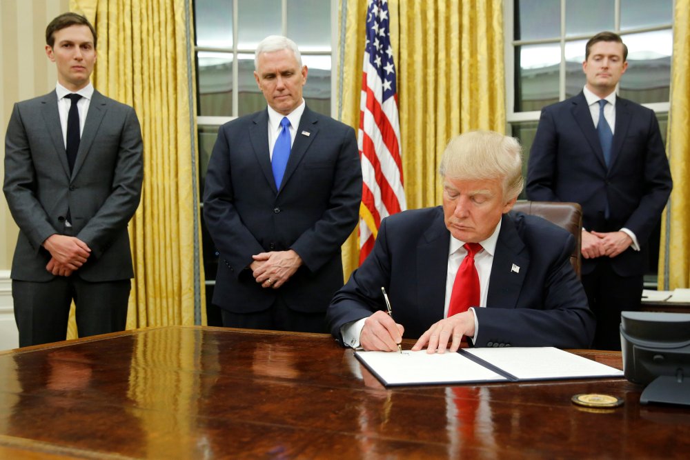 Image: Trump, flanked by Kushner, Pence and Porter, welcomes reporters into the Oval Office for him to sign his first executive orders at the White House in Washington