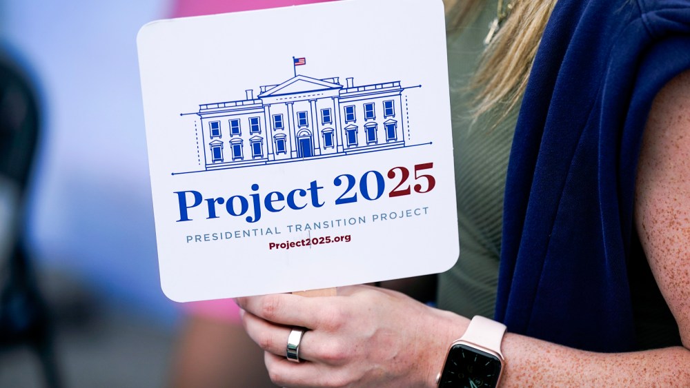 A fairgoer holds a Project 2025 fan at the Iowa State Fair in 2023.