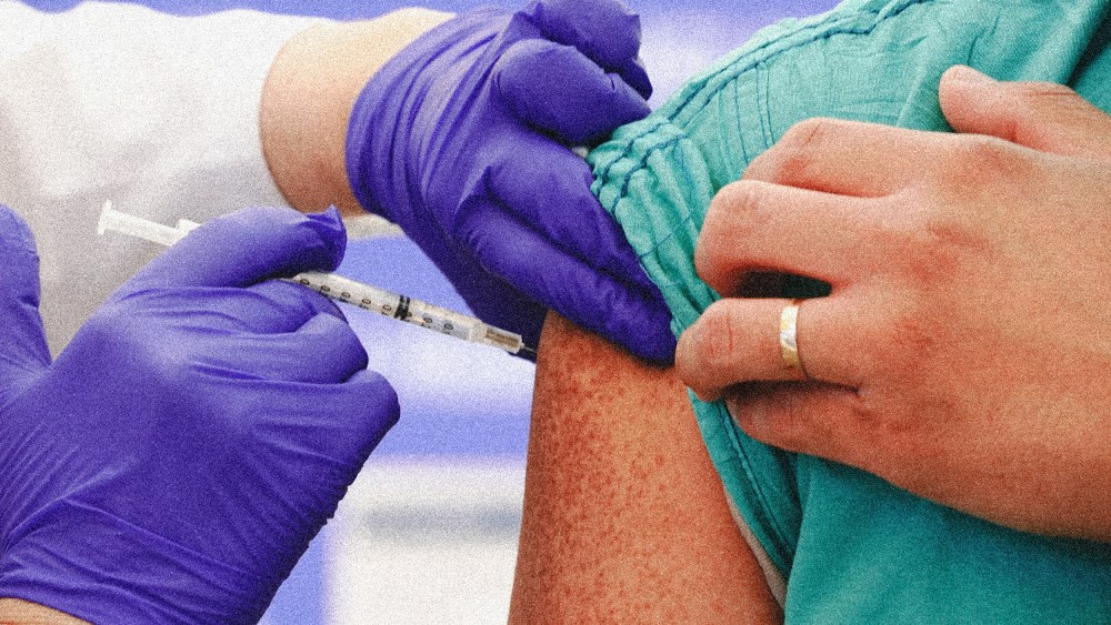 Image: Hands of a medical professional wearing surgical gloves holding a syringe.