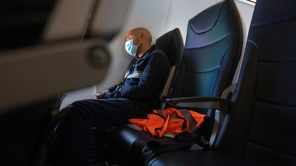 Image: A passenger wearing a protective mask sleeps during a flight.