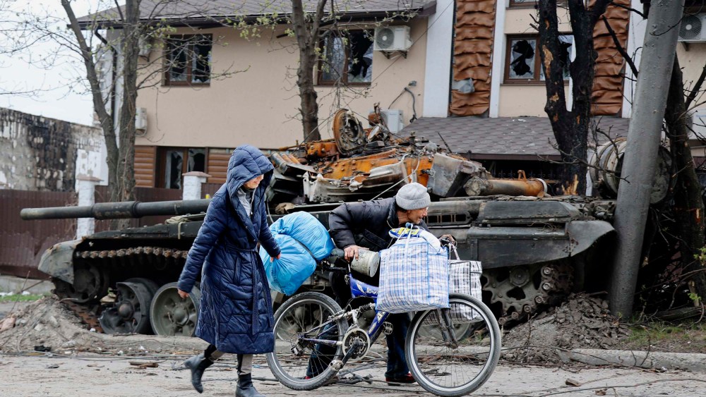 Local civilians walk past a tank destroyed during heavy fighting in an area controlled by Russian-backed separatist forces in Mariupol, Ukraine on Tuesday, April 19.