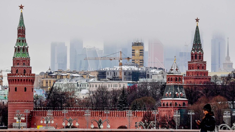 A woman walks in front of the Kremlin and skyscrapers of the Moscow International Business Centre in Moscow on December 17, 2020.