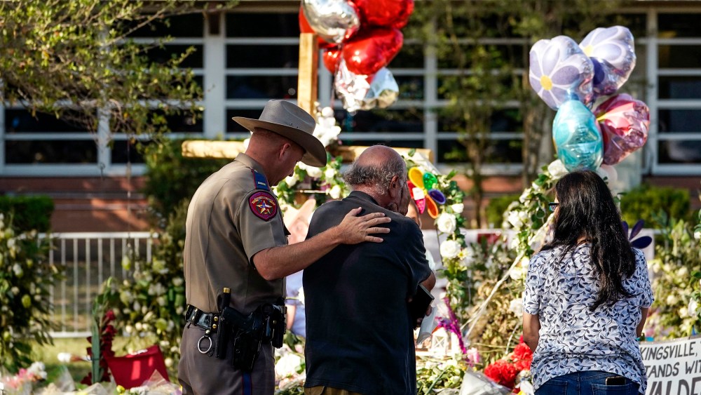 Image: A man is comforted by a Texas Department of Public Safety officer at a memorial outside Robb Elementary School created to honor the victims killed in last week's school shooting, on June 3, 2022, in Uvalde, Texas.