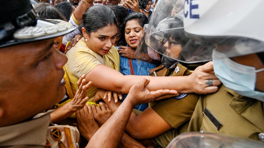 Former member of parliament Hirunika Premachandra, a politician and a leader of Samagi Vanitha Balawegaya, tries to jump over the barriers during a protest outside Sri Lanka's Prime Minister Ranil Wickremesinghe's private residence in Colombo on June 22.
