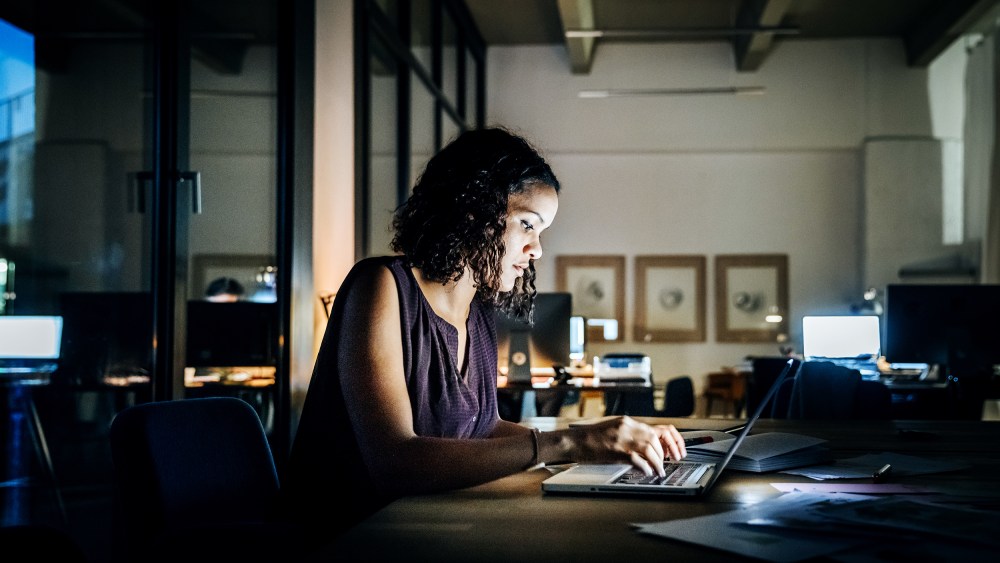 Casual young businesswoman working late on a laptop